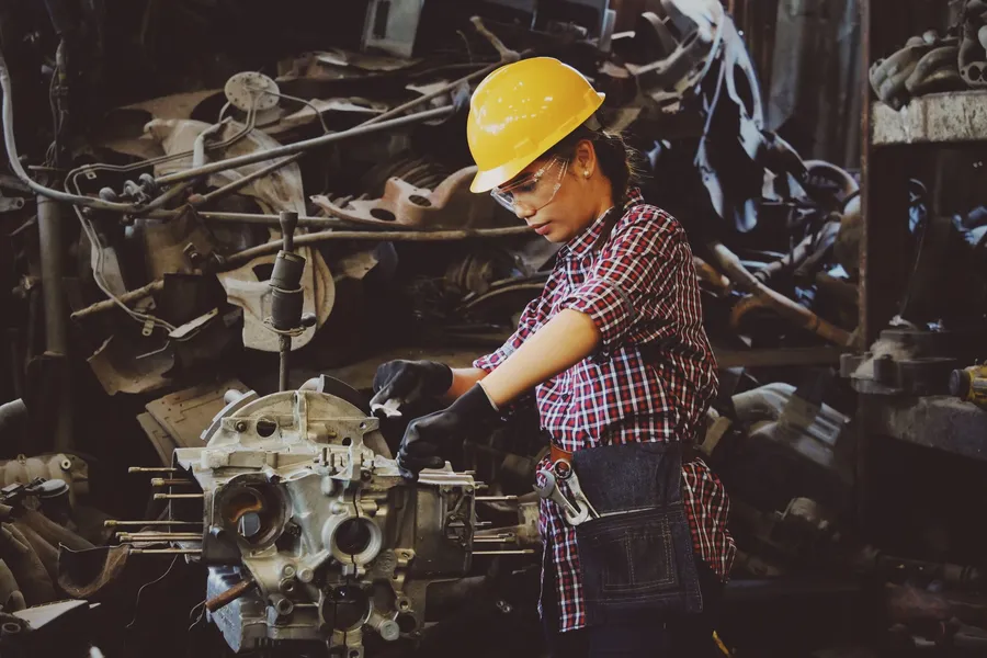 Technician in a hard hat and safety glasses working on an engine block
